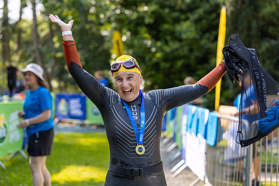 Image shows a smiling swimmer wearing a finisher medal